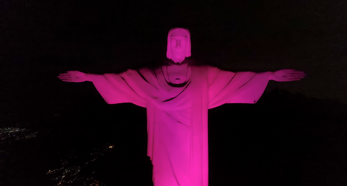 Cristo Redentor iluminado em rosa &agrave; noite, com a cabe&ccedil;a e os bra&ccedil;os vis&iacute;veis